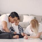 A family enjoying quality time together, drawing on the floor in a cozy living room setting.