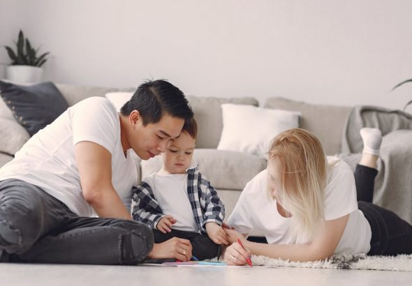 A family enjoying quality time together, drawing on the floor in a cozy living room setting.