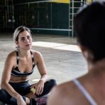 Two women in a workout session, sitting on the gym floor, focused and relaxed.
